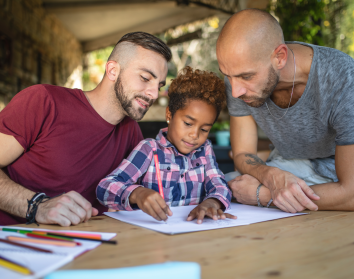 Two dads helping their child with homework