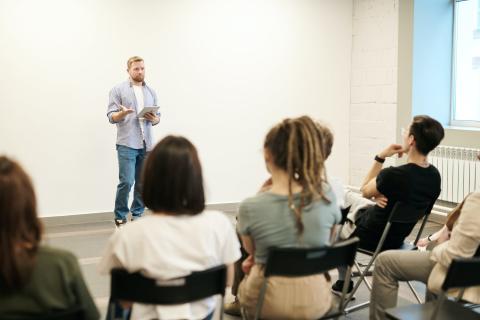 people sitting in chairs learning from someone standing up in front of them